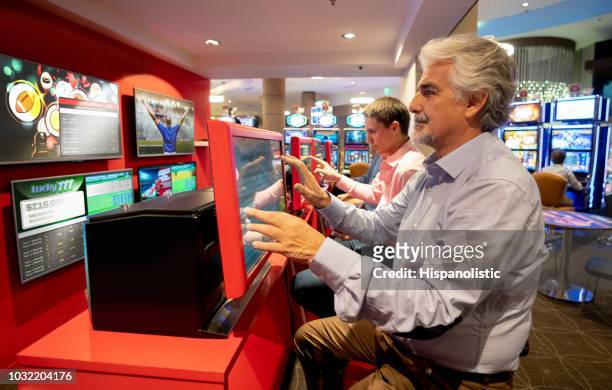 senior man bij het casino sportweddenschappen met behulp van een scherm - american football on screen stockfoto's en -beelden