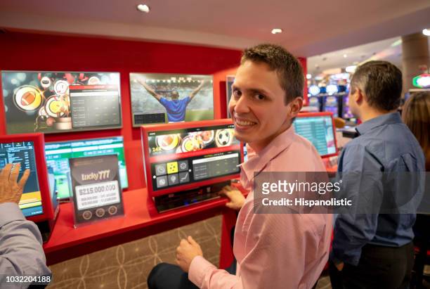 handosme junger mann, blick in die kamera lächeln beim sportwetten im casino - public liability stock-fotos und bilder