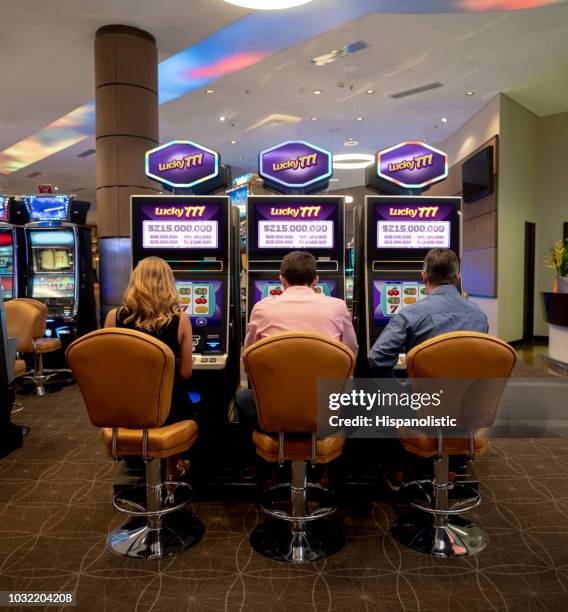 grupo de personas irreconocibles jugando en máquinas tragamonedas en el casino - slot machine fotografías e imágenes de stock