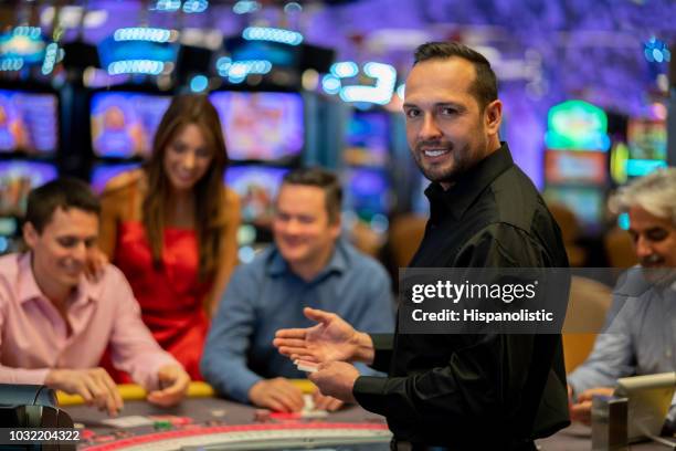 ritratto di rivenditore di carte al casinò guardando la fotocamera sorridente molto felice - croupier foto e immagini stock