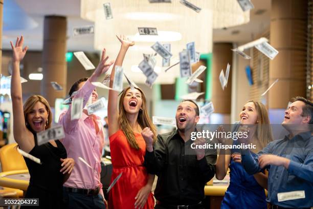 group of friends at the casino celebrating a big win throwing money to the air - casino win stock pictures, royalty-free photos & images