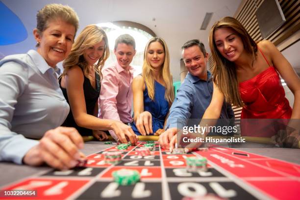 非常に興奮見ているルーレットのテーブル上のベットを置いている人々 の低角度のビュー - roulette table ストックフォトと画像