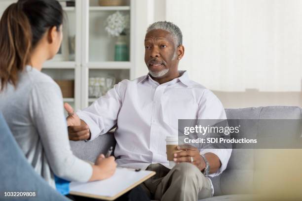 senior man talar öppet med uppmärksam terapeut - african american man depressed bildbanksfoton och bilder