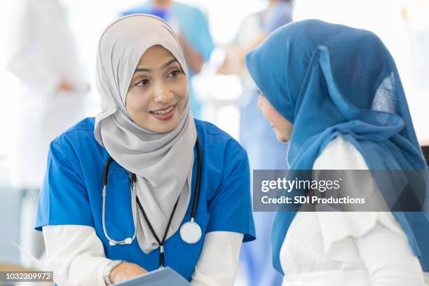 vrouwelijke arts praat met zwangere vrouw - pregnant muslim stockfoto's en -beelden