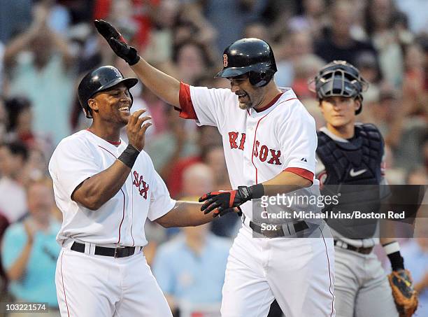 Mike Lowell of the Boston Red Sox is greeted at home plate by Adrian Beltre after hitting a two-run home run on the first pitch he saw against the...