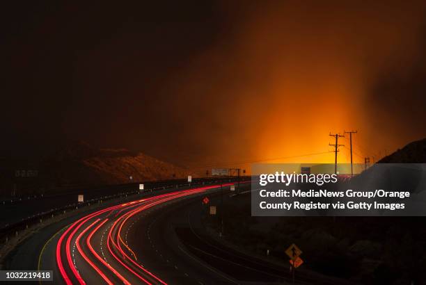 Flames glow as traffic drives north on the 15 Freeway, seen from the Highway 138 overpass, after it was reopened Wednesday night as firefighters...