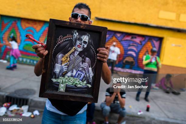 Mexican worshiper of Santa Muerte holds religious artwork during a pilgrimage on April 1, 2018 in Tepito, Mexico City, Mexico. Santa Muerte is a...