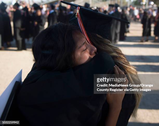 Graduate Ariana Figueroa, left, cries as she hugs her friend Jennifer Vazquez after the Los Amigos High School Graduation at Bolsa Grande Stadium in...
