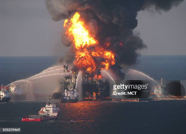 Fire boat response crews battle the blazing remnants of the offshore oil rig Deepwater Horizon April 21, 2010. A Coast Guard MH-65C dolphin rescue...