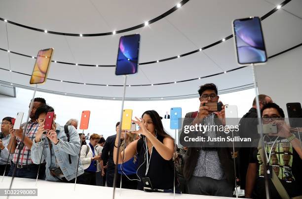 Visitors inspect the new iPhone X R during an Apple special event at the Steve Jobs Theatre on September 12, 2018 in Cupertino, California. Apple...