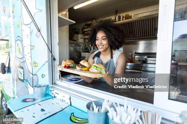 venditore di cibo femminile che offre panini in furgone per il cibo - furgone ambulante foto e immagini stock