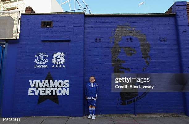 Young Everton supporter stands next to a mural outside Goodison Park prior to the pre-season friendly match between Everton and Everton Chile at...