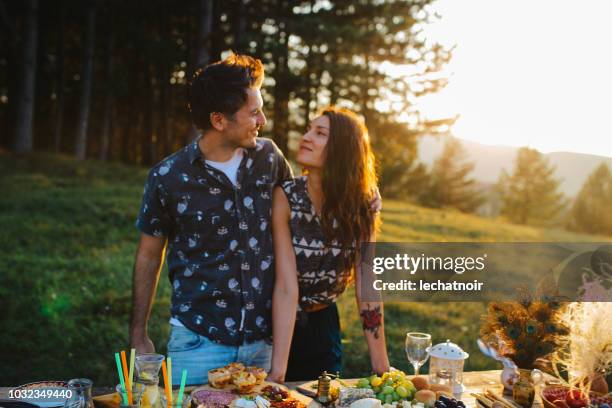 giovane coppia che prepara il cibo per il picnic in campagna - mangiare natura foto e immagini stock