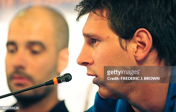 Barcelona's Argentinian midfielder Lionel Messi responds to questions while seated beside coach Pep Guardiola during a press conference in Beijing on...