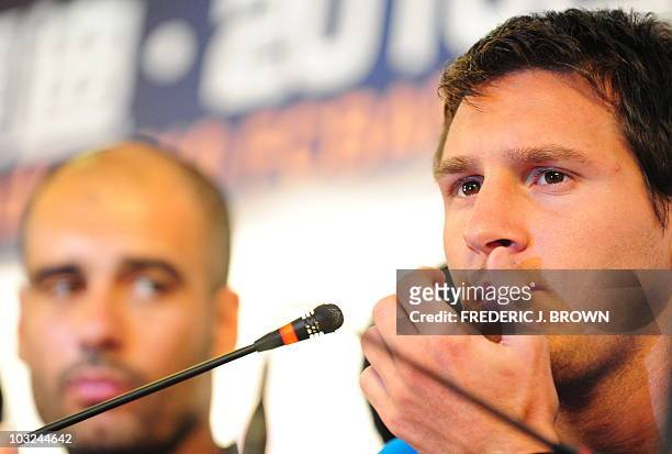 Barcelona's Argentinian midfielder Lionel Messi listens to questions as coach Pep Guardiola looks on at a press conference in Beijing on August 5,...