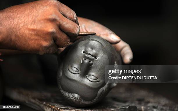 An Indian idolmaker works in clay to make a model of Hindu God Biswakarma in a workshop at Kumartoli, the artists' village in Siliguri on July 29,...