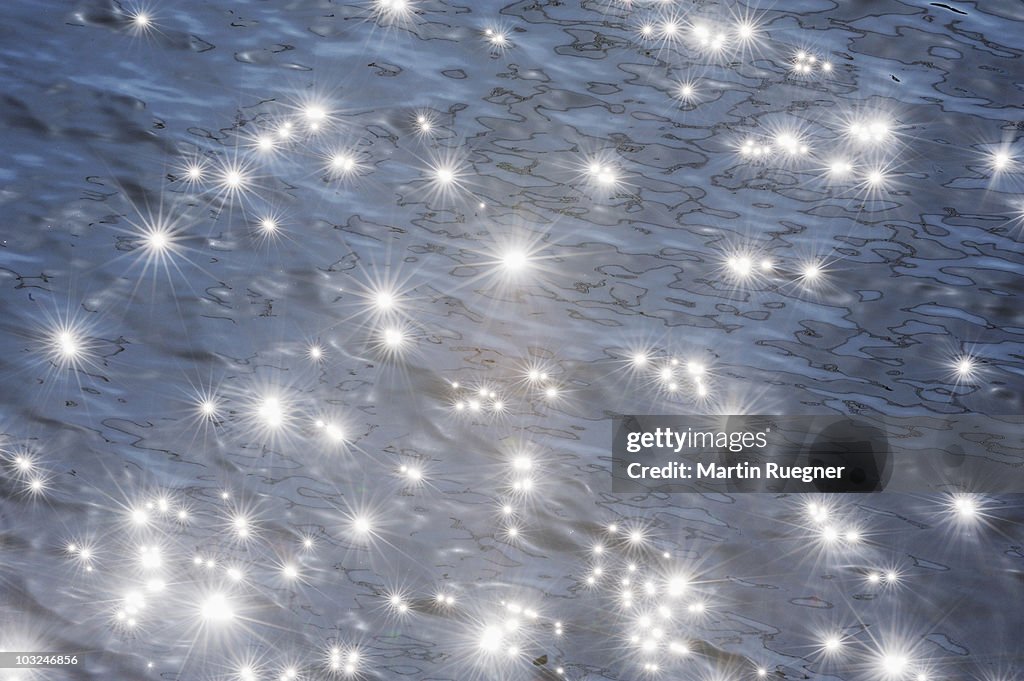 Sun reflecting in water surface with sunbeams.