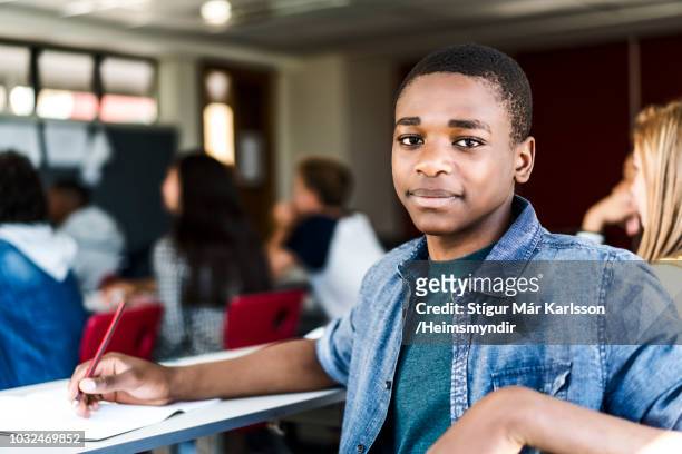 portrait of schoolboy with book at desk in class - black jacket stock pictures, royalty-free photos & images