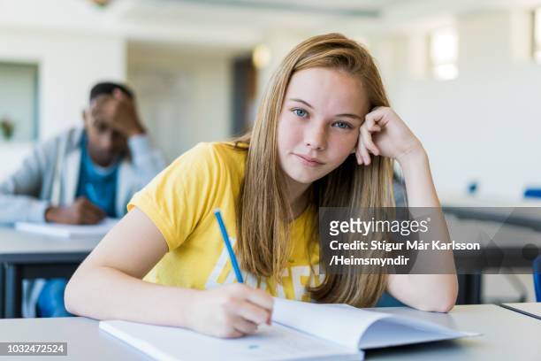 confident female student writing in book at school - 14 year old blonde girl stock pictures, royalty-free photos & images