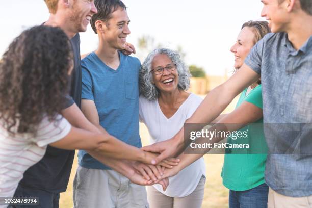 multiethnic group of adults puts their hands together for a cheer - baby boomer millennial stock pictures, royalty-free photos & images