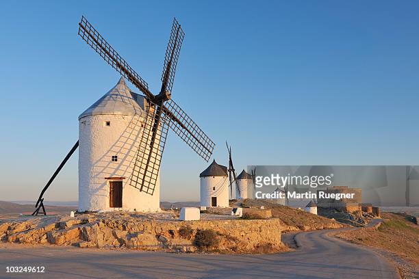 row of windmills with castle near consuegra. - castilië la mancha stockfoto's en -beelden
