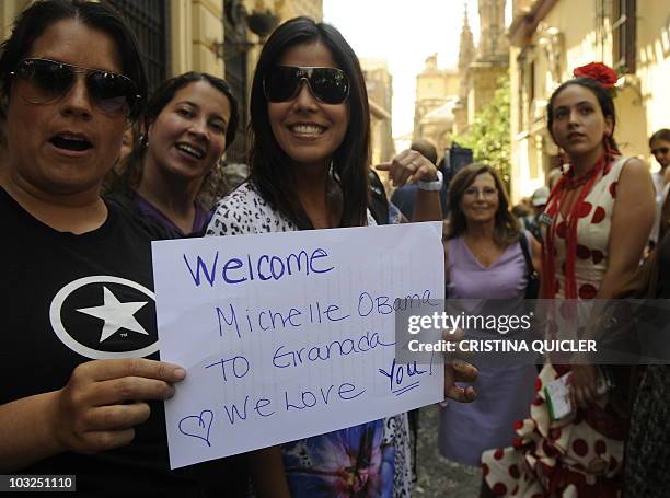 Young women hold a placard welcoming US First Lady Michelle Obama near Granada's cathedral on August 5 where Michelle Obama arrived for a visit. US...