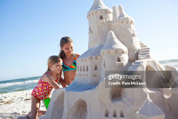 children building sand castle on the beach - sandburg stock-fotos und bilder