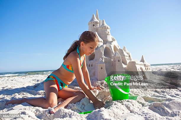 little girl building sand castle on the beach - kind sandburg stock-fotos und bilder