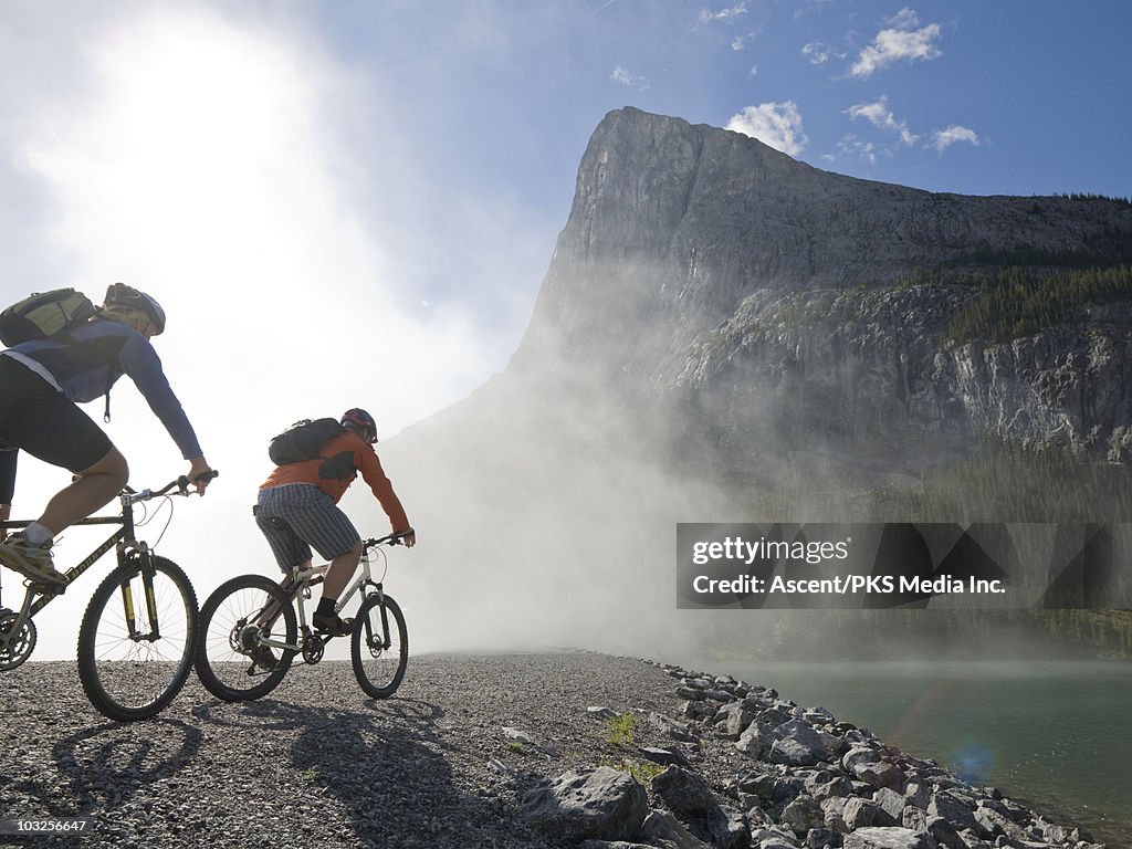 Couple bike into mist above mountain lake