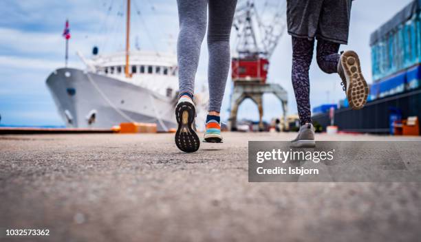 unbekannter athlet paar jogging am dock bei sonnenuntergang, nahaufnahme. - sole of shoe stock-fotos und bilder