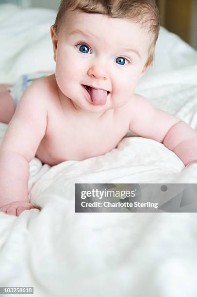 baby boy on bed. - sticking out tongue stock-fotos und bilder