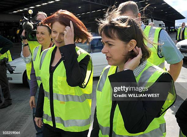 Australia's Prime Minister Julia Gillard and Minister of Health and Ageing Nicola Roxon adjust their hair as they arrive to tour a warehouse in the...
