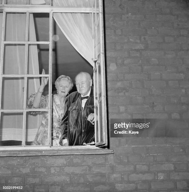 Sir Winston Churchill and his wife Clementine Churchill pictured together standing at an open window of their house in Kensington, London on 10th...