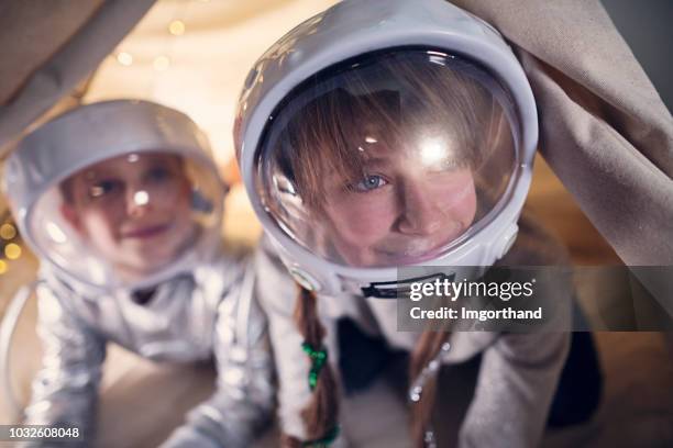 hermana y hermano jugar a astronautas en su habitación - casco espacial fotografías e imágenes de stock