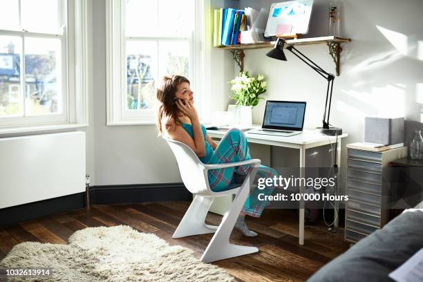 woman using mobile phone in home office and looking away - pajamas stock-fotos und bilder