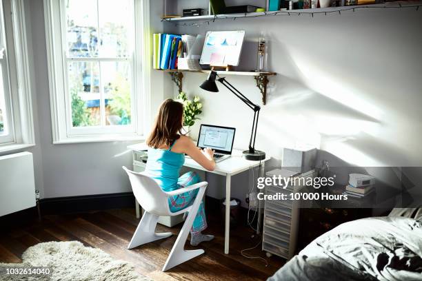 mid adult woman sitting at desk in bedroom using laptop - student accommodation stock pictures, royalty-free photos & images