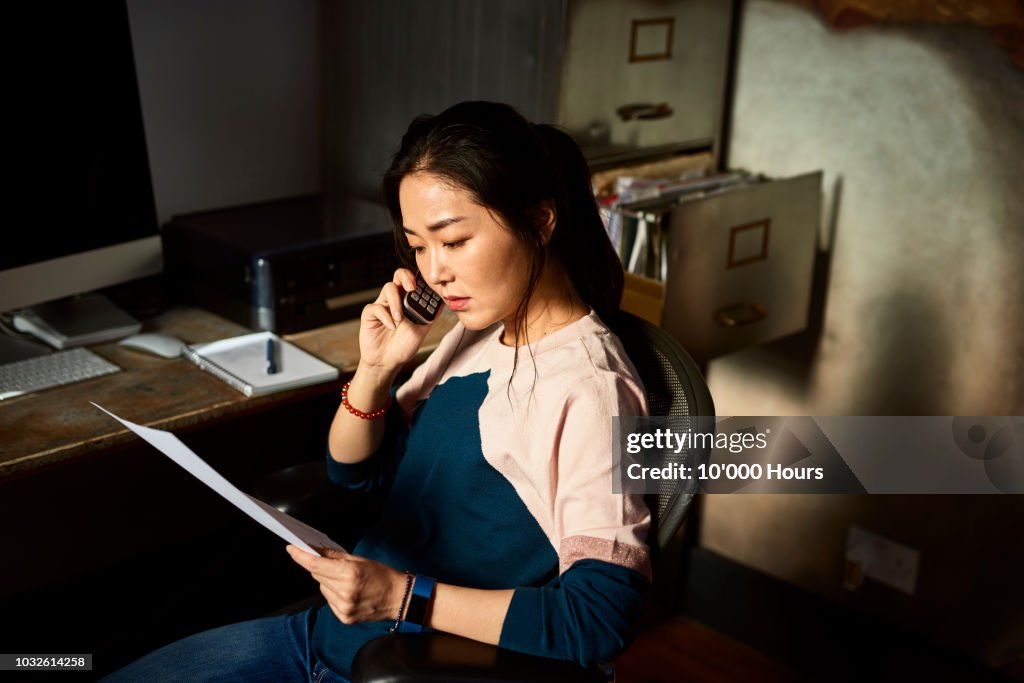 Portrait of Korean woman on cell phone reading important document