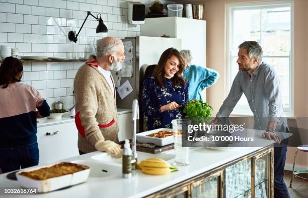 woman cutting fresh basil with husband and father in law in family kitchen - preparing food talking stock pictures, royalty-free photos & images