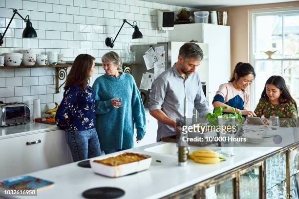 Lively relaxed three generation family gathering in kitchen