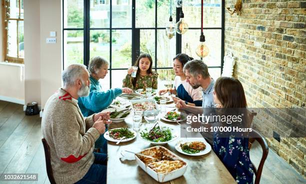 high angle shot of extended family eating dinner together - family at dining table stock pictures, royalty-free photos & images