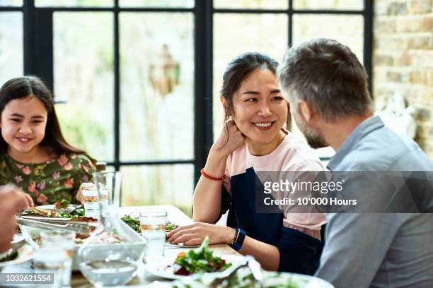 cheerful asian woman talking to husband and smiling at dinner table - asian couple dinner stock pictures, royalty-free photos & images