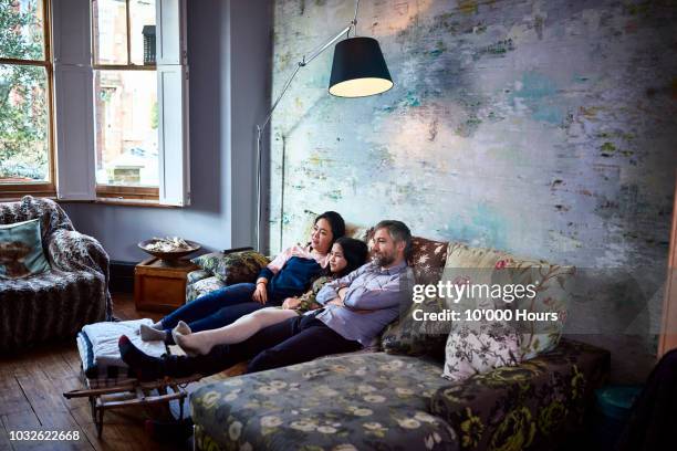 family watching television together at home on sofa - típico de clase mediana fotografías e imágenes de stock
