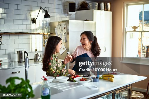 Mother teasing daughter in kitchen whilst making smoothies Mother teasing daughter in kitchen whilst making smoothies
