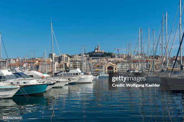 The Vieux Port with boats in Marseille, France with the Notre-Dame de la Garde , a Catholic basilica in the background.