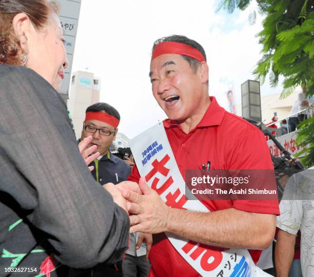 Ruling Liberal Democratic Party backed candidate Atsushi Sakima shakes hands with his supporter as the Okinawa gubernatorial election officially...