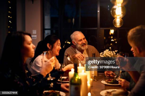 cheerful guests at dinner table listening to friend and drinking wine - asian food fotografías e imágenes de stock