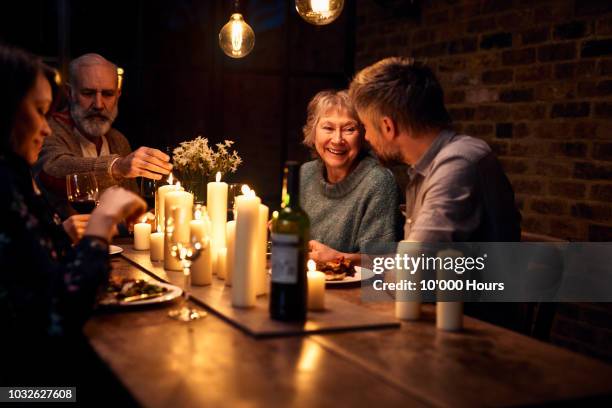 cheerful senior woman listening to son in law and smiling - aangetrouwde relaties stockfoto's en -beelden