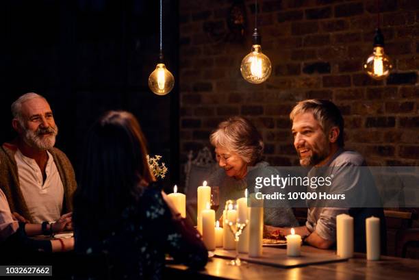 relaxed family group enjoying candlelit dinner together - evening meal stock pictures, royalty-free photos & images