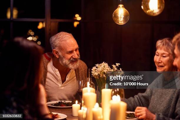 mature man talking at dinner party and smiling with family - evening meal stock-fotos und bilder