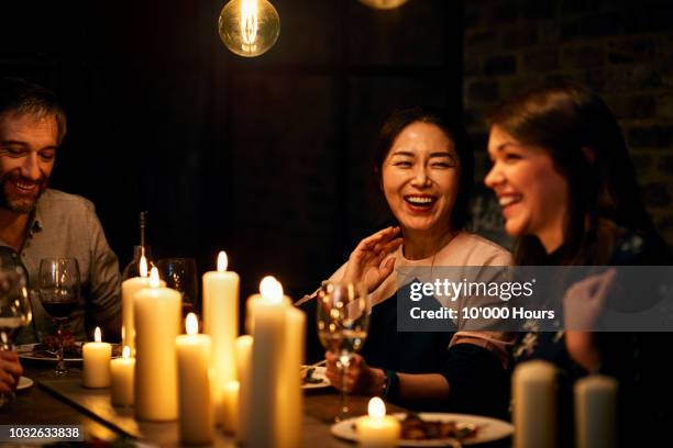 two female friends sitting next to each other and laughing during meal - restaurant night ストックフォトと画像